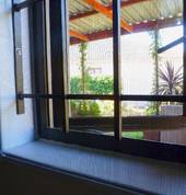 White insect screen installed onto wall around burglar bars