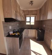 A renovated kitchen, floor and wall tiled.Ceiling designs.Greyish brown theme.